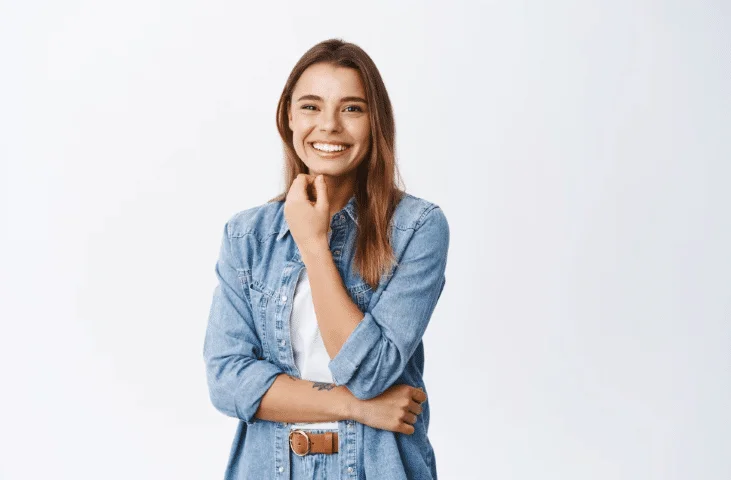 homem sorridente vestindo um sobretudo preto e camisa social branca, com os braços cruzados e posicionado de forma casual.