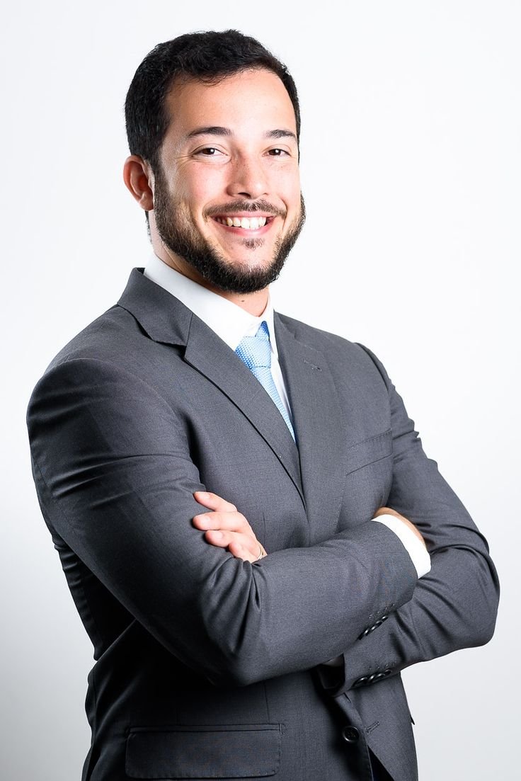 Retrato profissional de um homem barbado sorridente, vestindo camisa social e gravata.